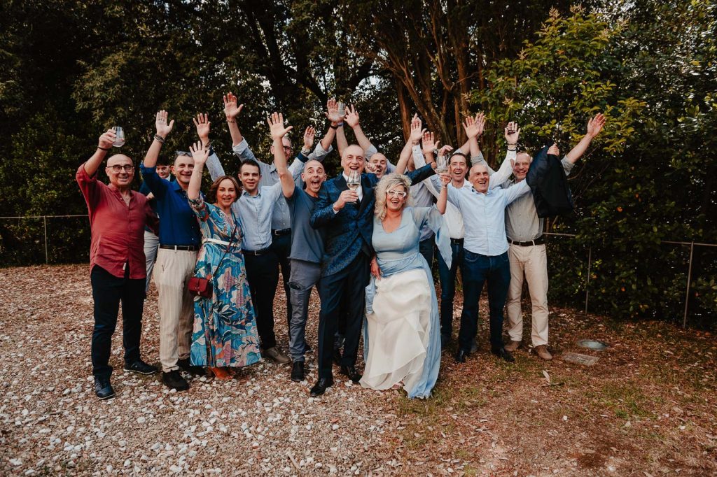 Gruppo di invitati sorridenti con le braccia alzate durante il matrimonio