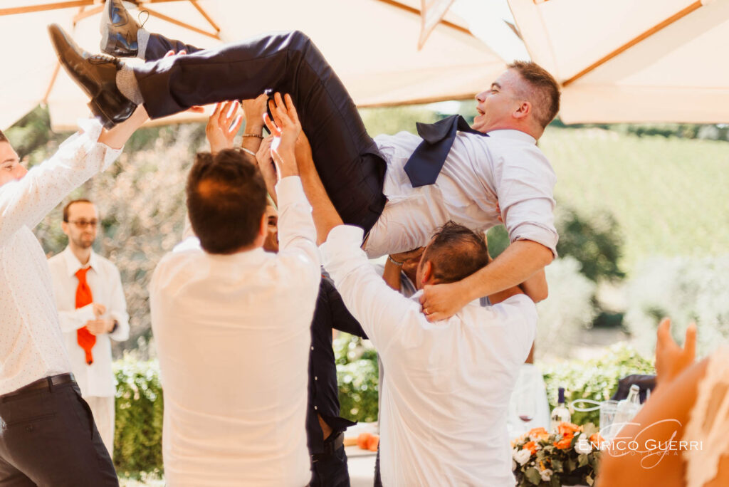 Sposo sollevato dagli amici durante la festa di matrimonio