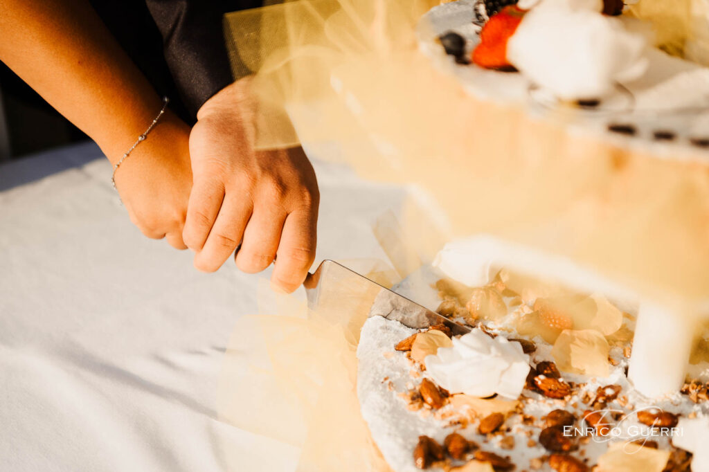 Mani degli sposi durante il taglio della torta nuziale