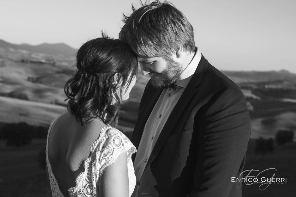 Sposo abbraccia la sposa da dietro mentre le tiene la mano